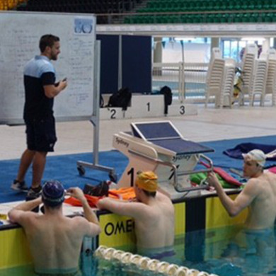 Coach standing at a white board leading a training session