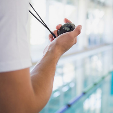 Coach at a pool holding a stopwatch