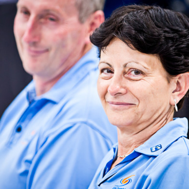 A male and female Technical Official working at a meet in blue shirts