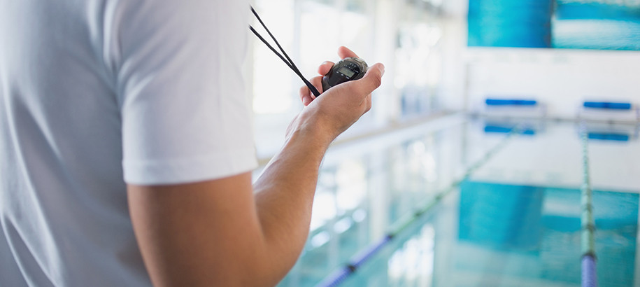 Coach at a pool holding a stopwatch