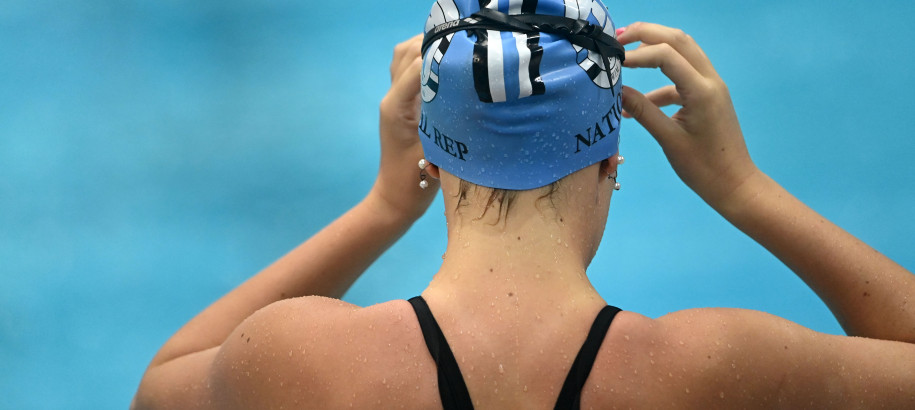back of female swimmer fixing goggles