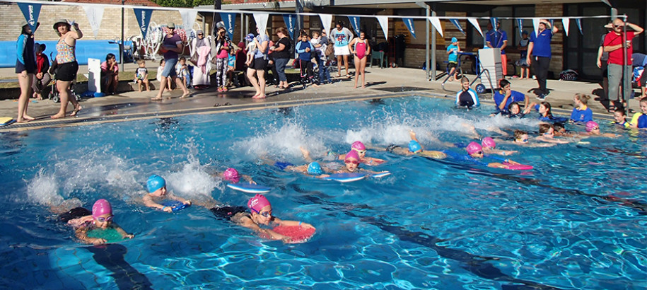 Junior swimmers having fun in a kick board race at a come and try event
