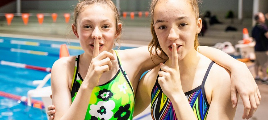 Two young female swimmers shooshing audience members