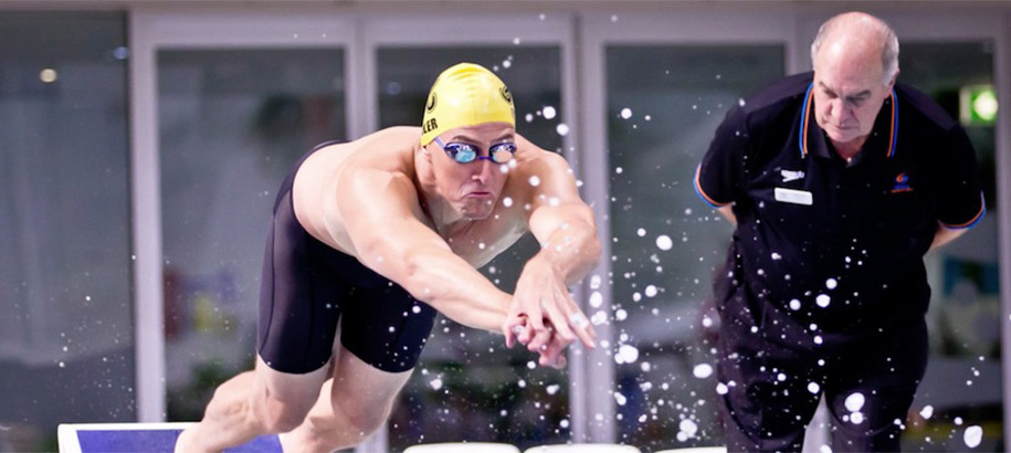 Inspector of Turns watching a swimmer dive in to a pool