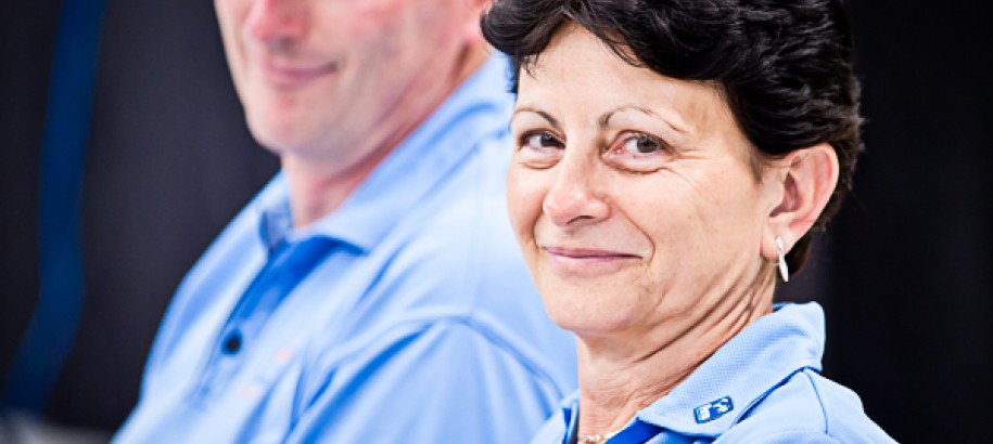 A male and female Technical Official working at a meet in blue shirts